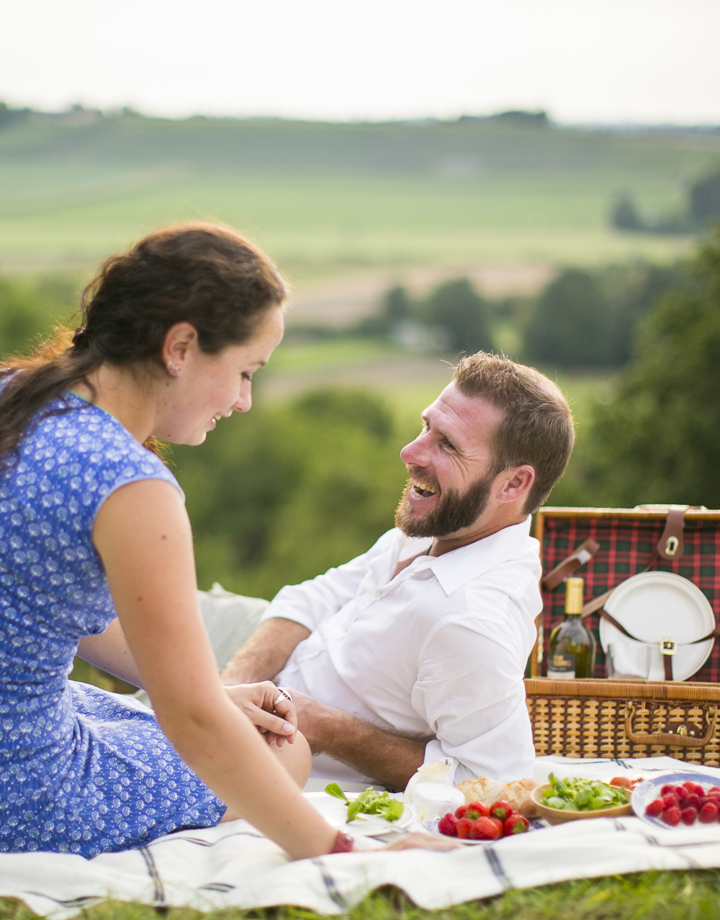 Man en vrouw genieten op weide van een picknick met achterliggend heuvellandschap